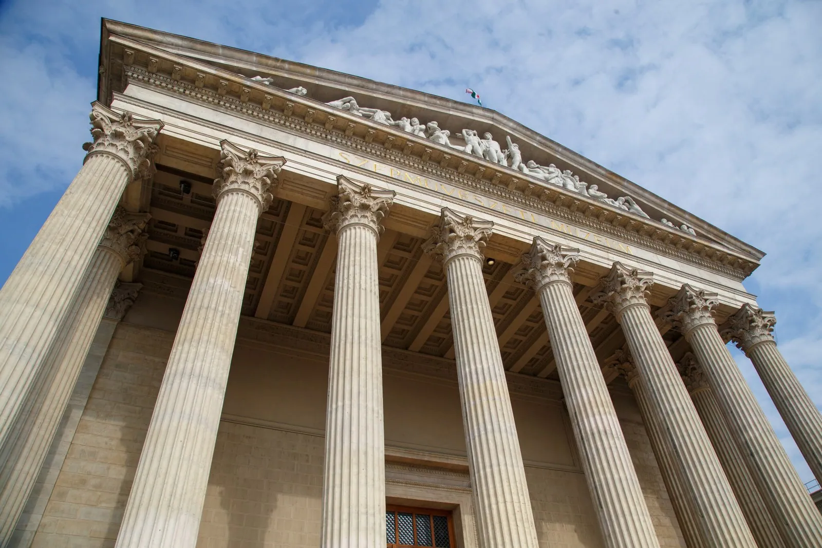 The columns of a courthouse against a blue sky